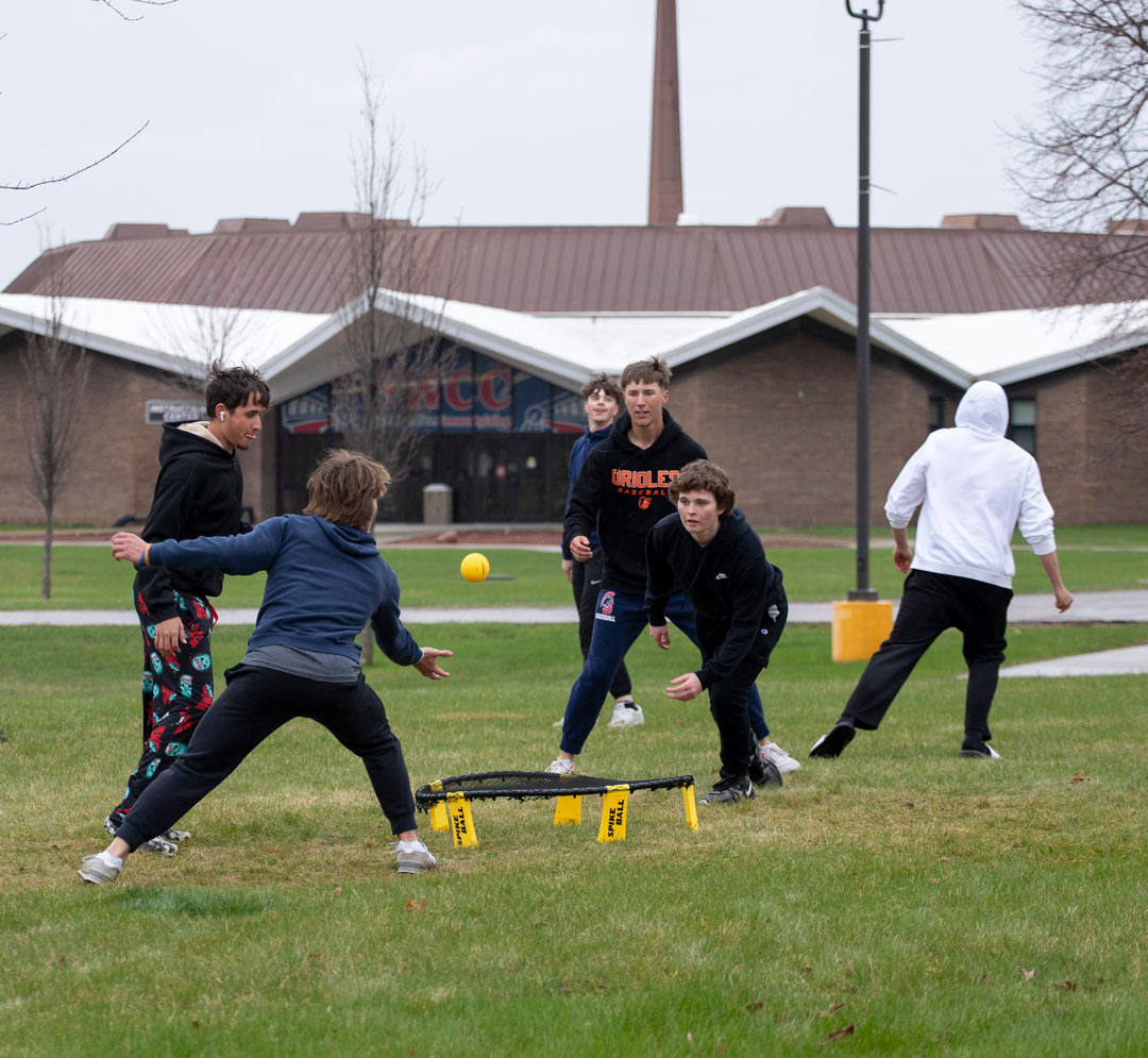 group of students playing spikeball with the Instructional Center in the background