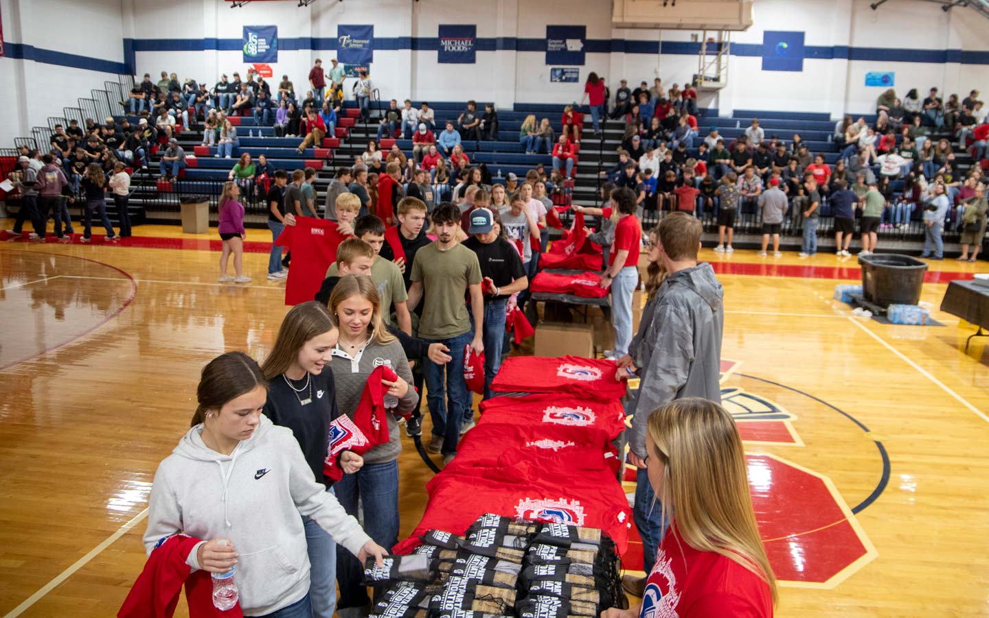 Students in line to receive giveaways with more students in background on bleachers