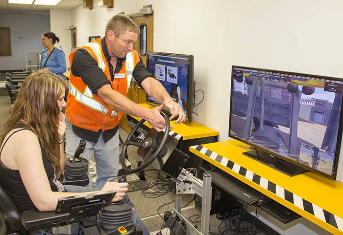 Woman operating simulator with employee assisting