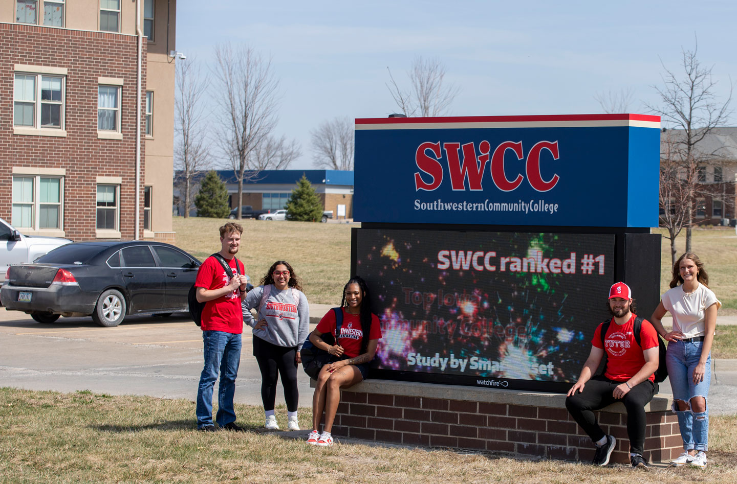 SWCC students standing by LED sign near campus main entrance