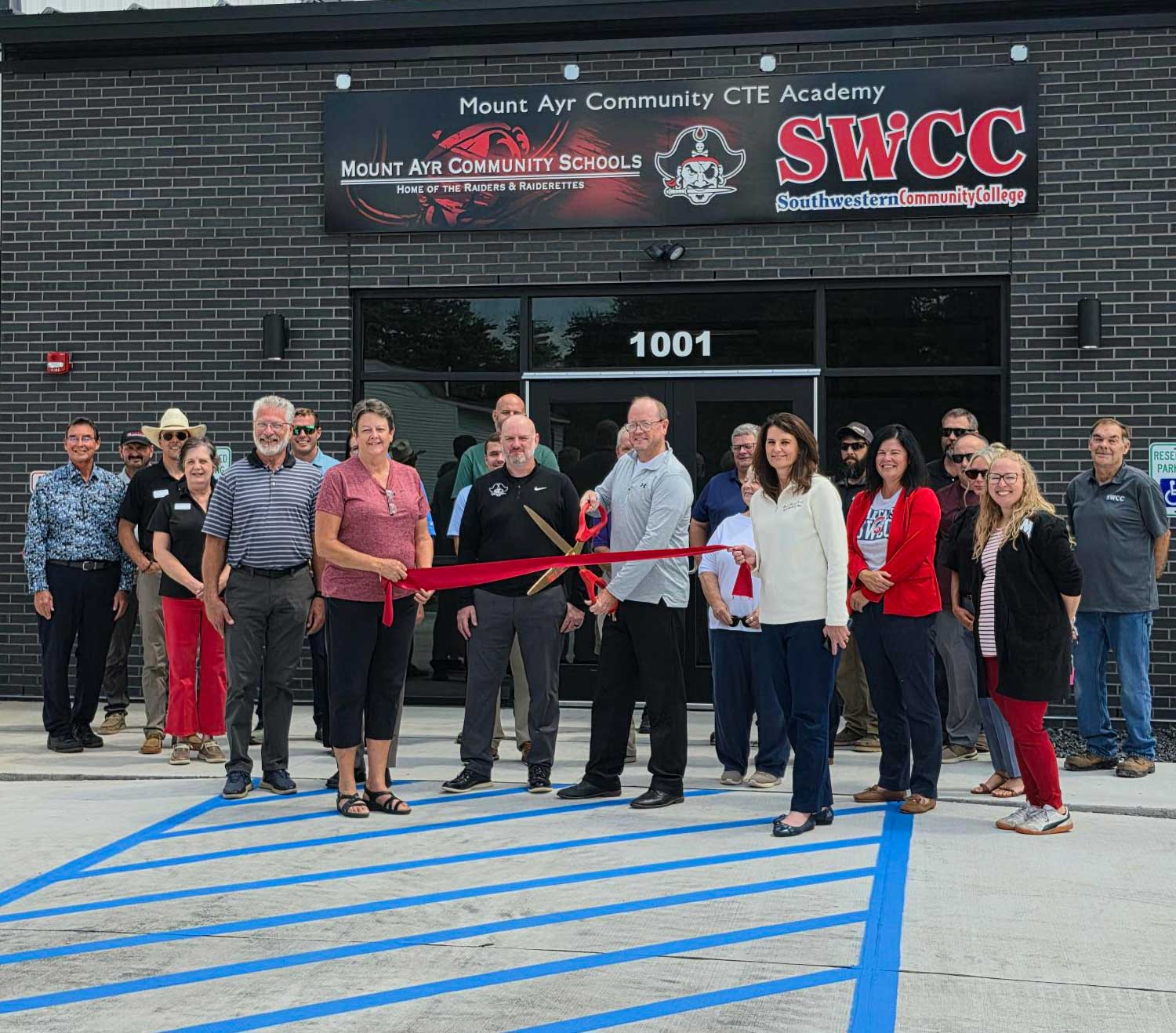 Everyone in attendance in front of the building getting ready to cut a big red ribbon