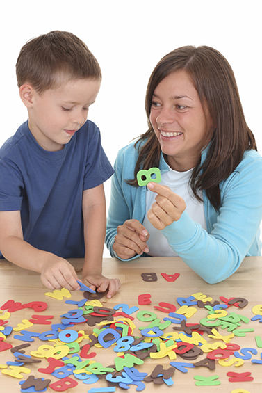 Female early childhood education professional working with child using cutout letters