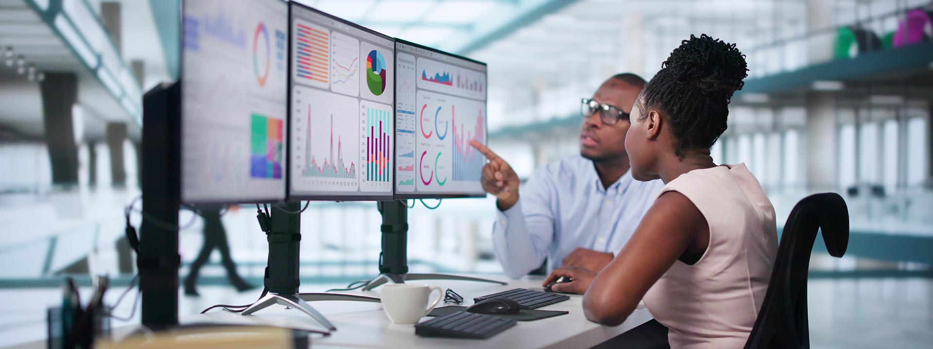 two people looking at computer screens with charts and graphs