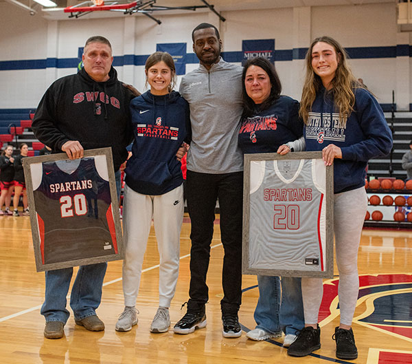 Women’s basketball coach Darien Wingate  presents Maddie’s parents and sisters with her framed jerseys.