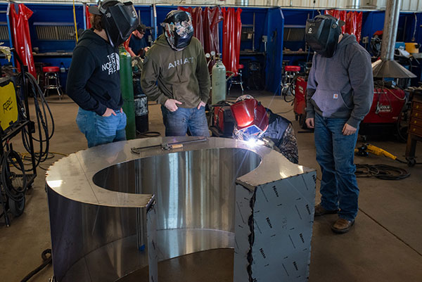 Welding students TIG welding one of the SWCC logo letters