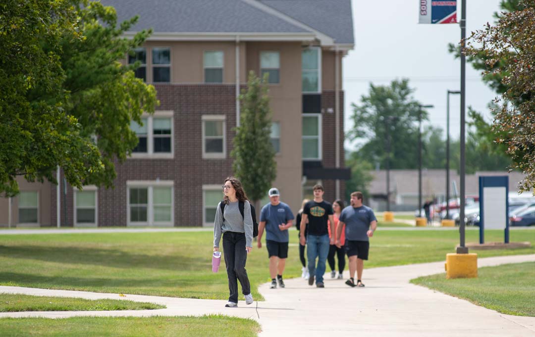 Student walking around campus with Spartan Hall in the background