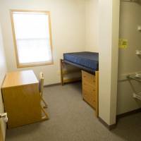 basic room setup with a lofted bed, dresser, and desk.