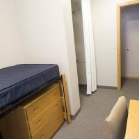 basic room setup with a lofted bed, dresser, and desk.