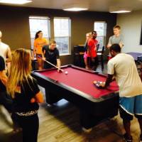 Students gathered around a pool table and playing various games in the commons area.