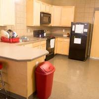 Shared kitchen with stool seating, oven, microwave, refrigerator, and cupboards.