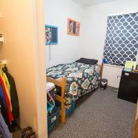 Single room with bed, desk, dresser, and closet