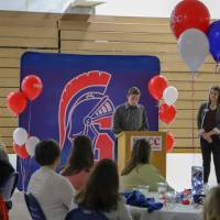 Student giving a speech during dinner with people looking on
